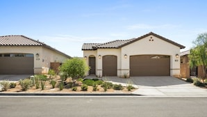 A residential property with a two-car garage, a landscaped front yard, and a clear sky. - Play Paradise: Pool+Spa, BBQ, GameRoom, PGA West! (La Quinta)
