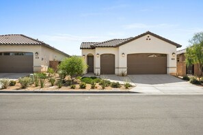 A residential property with a two-car garage, a landscaped front yard, and a clear sky. - Play Paradise: Pool+Spa, BBQ, GameRoom, PGA West! (La Quinta)