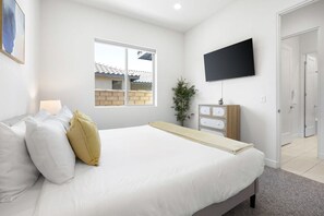 A bedroom with a bed, a television, a window, and a door. - Play Paradise: Pool+Spa, BBQ, GameRoom, PGA West! (La Quinta)