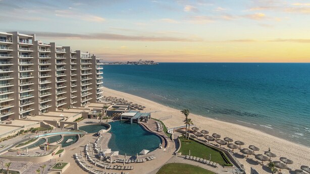 Een hoog hotel met een zwembad, toegang tot het strand en uitzicht op de oceaan.