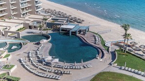 Een resort met een groot zwembad, ligbedden en een strandgedeelte.