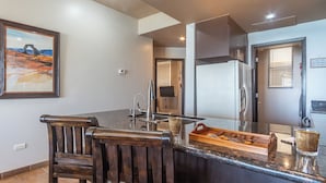 Een keuken met een granieten aanrechtblad, roestvrijstalen apparatuur en een houten stoel.