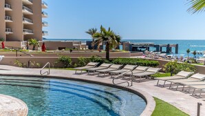 Area piscina con lettini, una palma e vista sull'oceano.