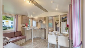 A compact living space with a kitchenette, a dining area, and a seating area with a sofa and chairs. - Pet friendly (sta)caravan in Irrhausen (Irrhausen)