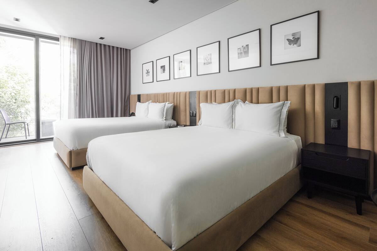 Una habitación de hotel moderna con dos camas, un ventanal grande y un balcón.