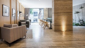 Een moderne woonkamer met een bank, eethoek en een groot raam.