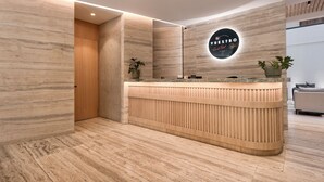 Een moderne receptiebalie met een houten afwerking, een rond bord erboven en potplanten aan weerszijden.