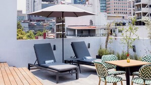 Een dakterras met lounge stoelen, een tafel en een parasol.