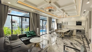 A modern living room with a sofa, a round coffee table, and a dining area with chairs. - Phoenix Villas FLC Ha Long (Ha Long)