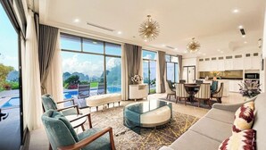 A spacious living room with a large window, a dining area, and a kitchen. - Phoenix Villas FLC Ha Long (Ha Long)