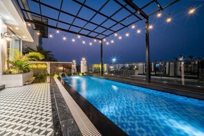 A rooftop pool with string lights, a sign reading 'An Villa,' and a patterned floor.