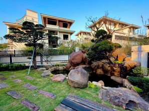 A residential area with a pond, rocks, and a wooden deck.