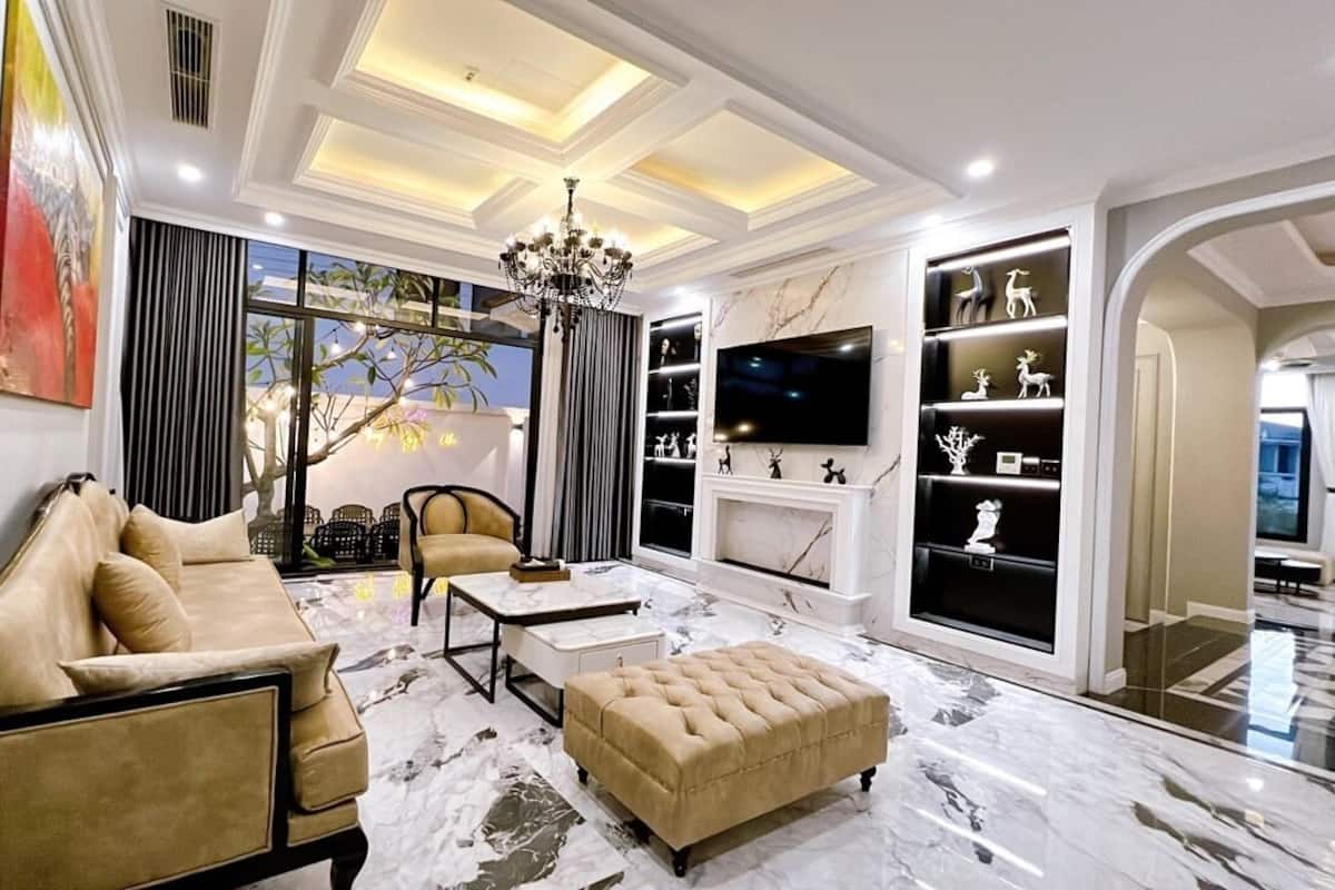 A modern living room with a sofa, ottoman, and coffee table, a fireplace, and a TV mounted on the wall.
