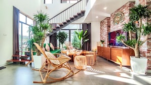 A spacious living area with a staircase, large windows, and multiple plants. - Phoenix Villas FLC Ha Long (Ha Long)