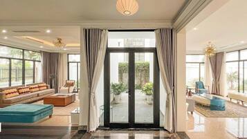 A spacious living room with a large sliding glass door leading to a patio, furnished with a sofa, coffee table, and a blue ottoman.
