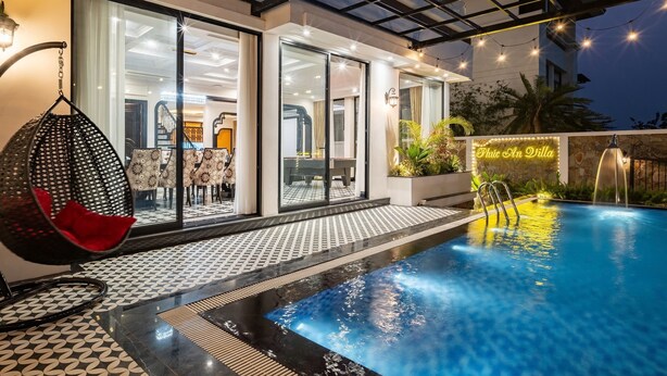 A modern outdoor pool area with a glass-enclosed patio, a hanging chair, and a sign reading 'Cafe on the Villa.' - Phoenix Villas FLC Ha Long (Ha Long)