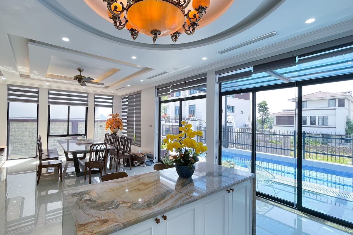 A spacious kitchen with a marble countertop, large windows, and a ceiling fan.