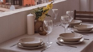 Mesa de comedor preparada para cuatro personas, con vista a un paisaje urbano al atardecer.