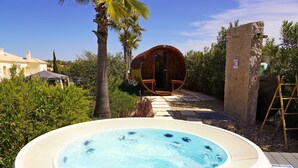 A hot tub with a wooden barrel structure in the background, surrounded by greenery and a clear sky. - Spa Suite 3: Pool, Jacuzzi & Sauna (Poço Partido)