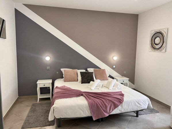Un dormitorio con cama, mesitas de noche, un ventanal grande y una escalera.
