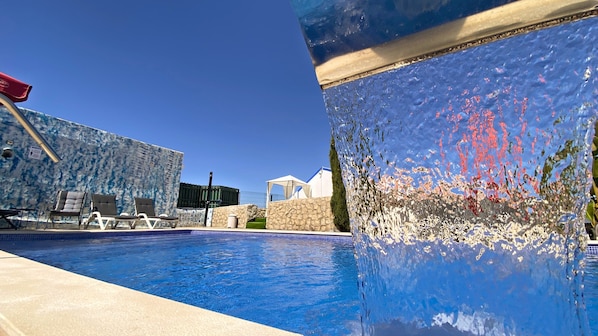 A swimming pool with lounge chairs and a stone wall. - Spa Suite 5: Pool, Jacuzzi & Sauna (Poço Partido)