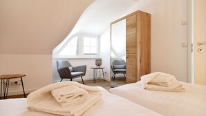 Ein Hotelzimmer mit zwei Betten, einem Holzschrank, einem kleinen Tisch, zwei Stühlen und einem großen Spiegel.
