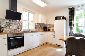 A modern kitchen with white cabinets, a built-in oven, a microwave, and a coffee maker on the countertop.