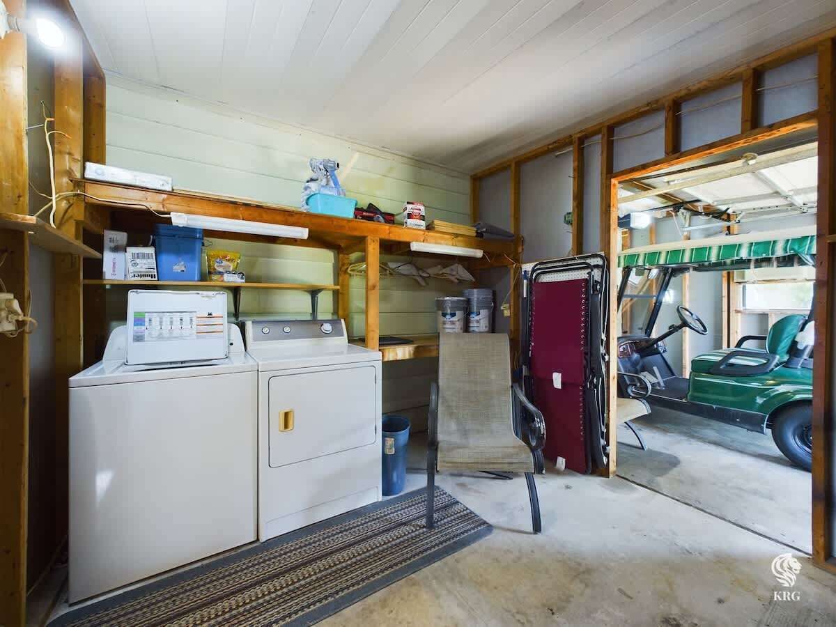 Een wasruimte met een wasmachine, droger en planken met diverse spullen.