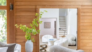 Un salón acogedor con un sofá blanco, un sillón mullido y una pared de madera.