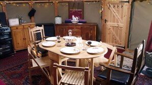 A round wooden dining table set for four with plates, glasses, and a centerpiece.