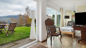 Una habitación amplia con una cama, un televisor y vistas al exterior.