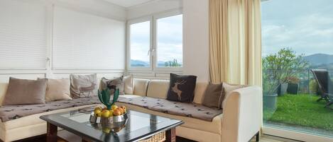 Een woonkamer met een bank, een bijzettafeltje met fruit en uitzicht op het landschap.