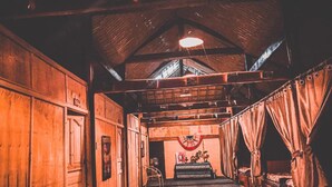 A rustic interior with wooden walls, a high ceiling, and a central area with a table and chairs. - Long Co Tran Homestay (Lung Cu)