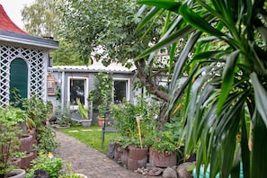 A garden pathway leading to a house with a red roof, surrounded by potted plants and a lattice structure. - Room 'Zimmer 2' with Wi-Fi (Zehdenick)