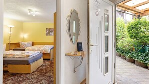 A room with two beds, a bedside table, a mirror, and a door leading to a garden. - Room 'Zimmer 2' with Wi-Fi (Zehdenick)
