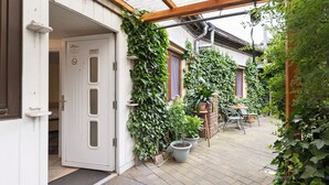 A white building with a door, potted plants, and a covered patio area. - Room 'Zimmer 2' with Wi-Fi (Zehdenick)
