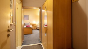 A hotel room with a wooden wardrobe, a bed with pillows, a bedside table, and a small window. - Room 'Zimmer 4' with Wi-Fi (Zehdenick)