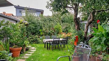 A garden with a table and chairs, surrounded by potted plants and a tree.