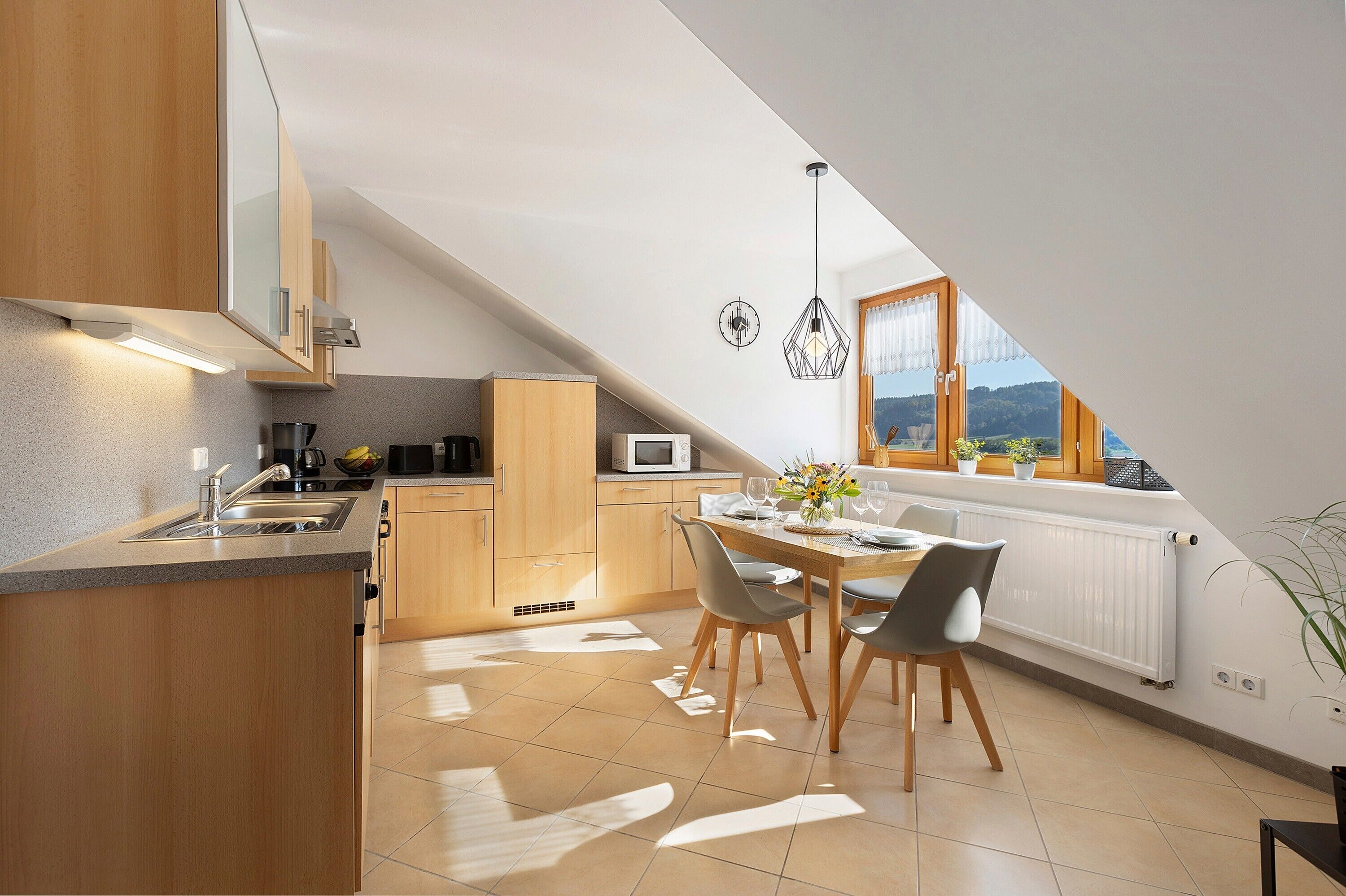 A modern kitchen with a dining area, wooden cabinets, a microwave, and a view of the outdoors.