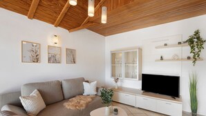 Uma sala de estar moderna com sofá, televisão e objetos decorativos.