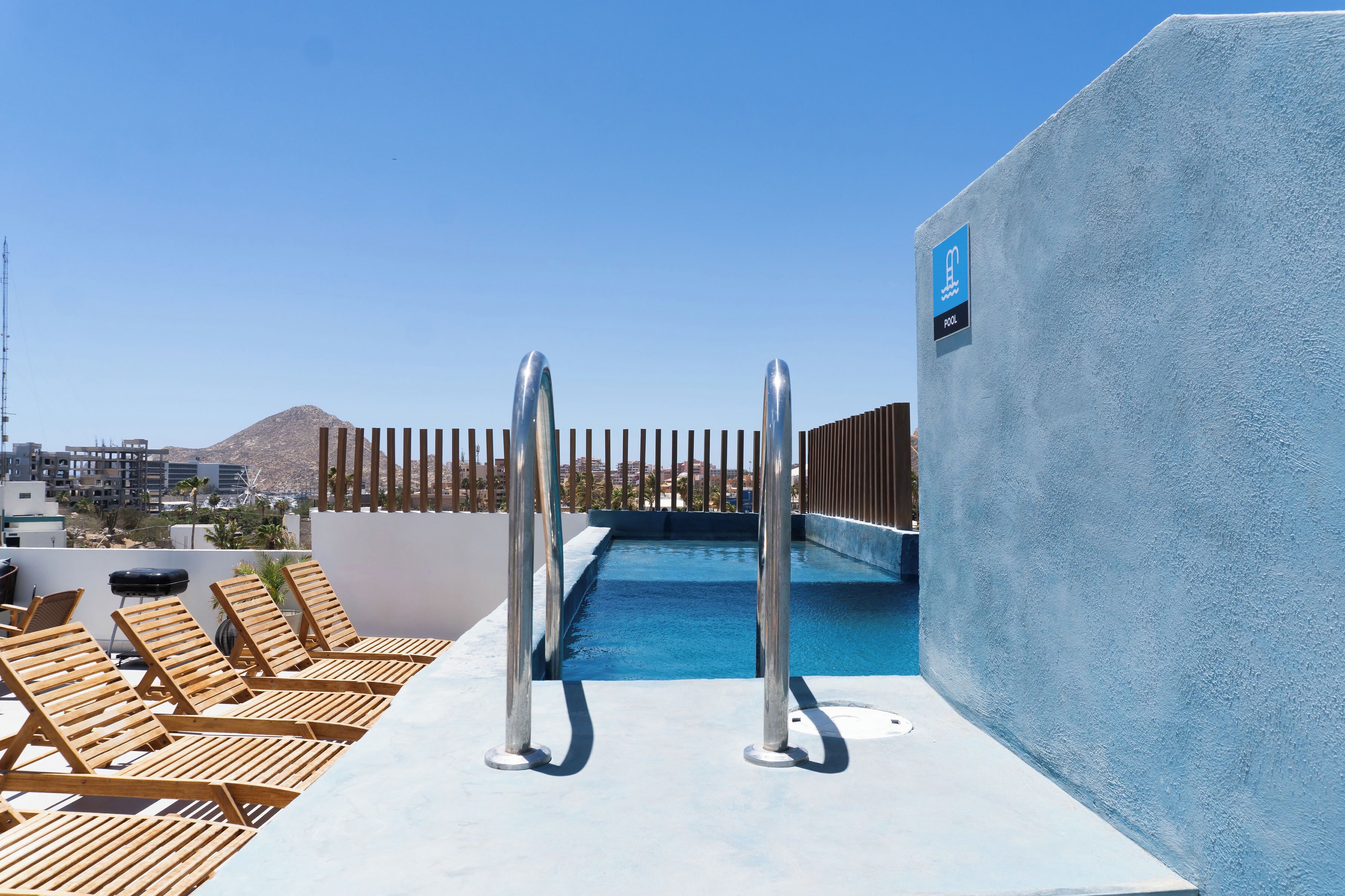A rooftop pool area with lounge chairs and a pool.