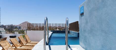 A rooftop pool area with lounge chairs and a pool.