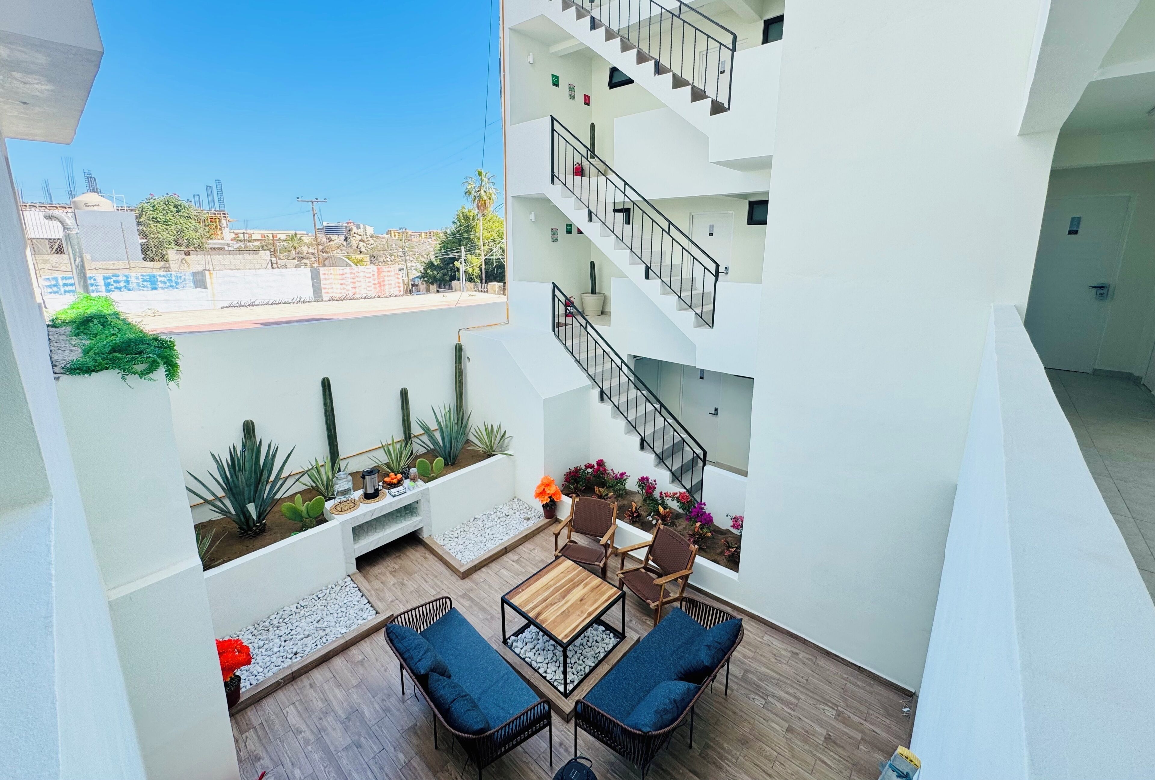 A modern apartment with a balcony, furnished with a table and chairs, and a small garden area with plants and flowers.