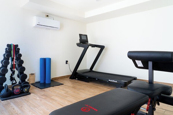 A gym with a treadmill, weight bench, and kettlebells. - Colmena Hotel Los Cabos Marina (Cabo San Lucas)