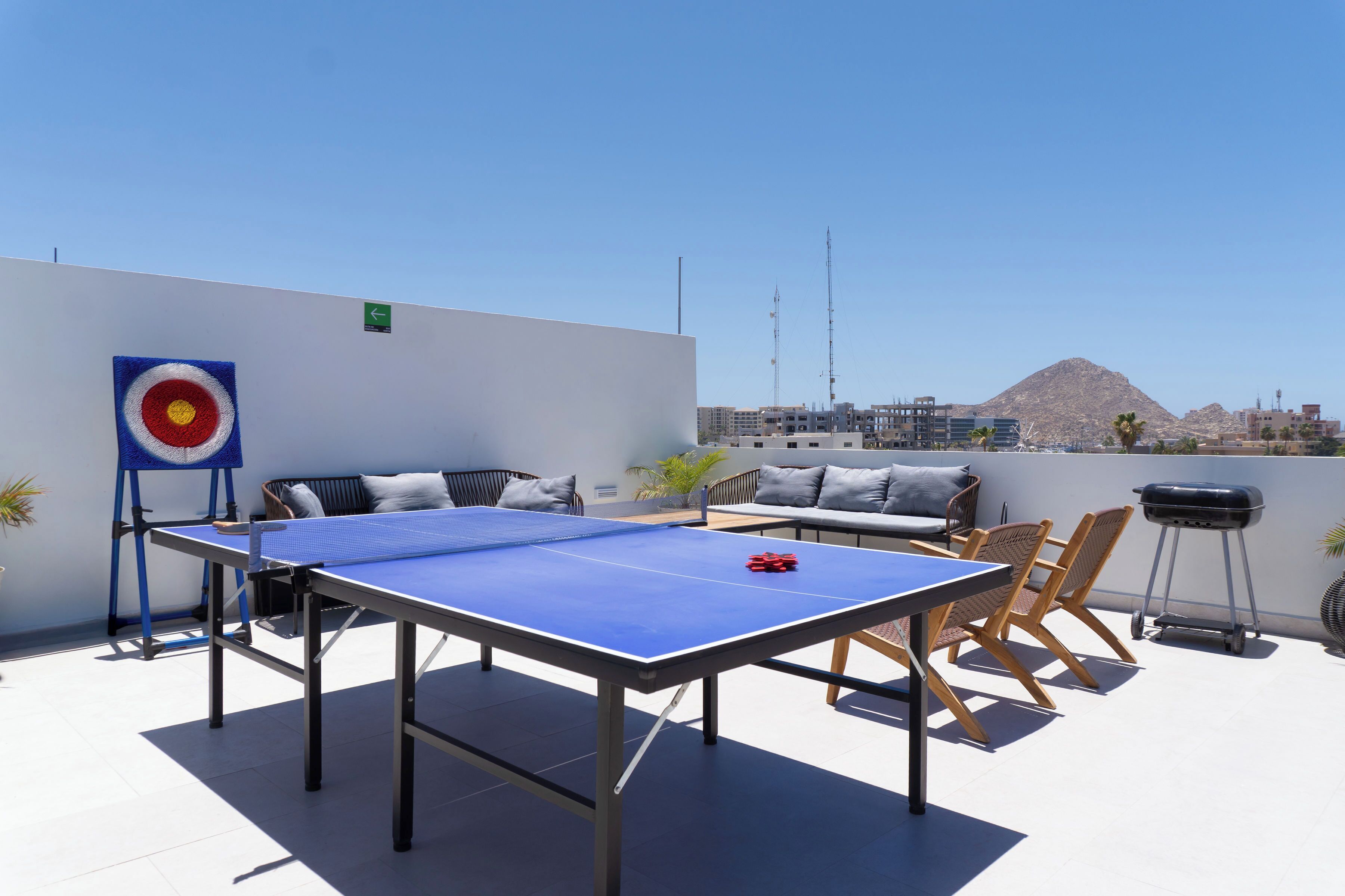 Terraza en la azotea con mesa de ping pong, zona de estar y parrilla.