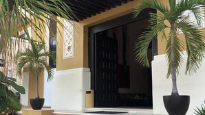 A building entrance with a covered porch, steps leading up to the door, and potted plants. - 2 BR with infinity adult pool + family pool, ocean view, & best street in Playa! (Playa del Carmen)