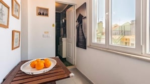 A narrow hallway with a wooden bench, a small table with oranges, and framed pictures on the wall. - GuestReady - One prime stay in Lisbon (Lisbon)
