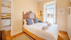 A bedroom with a wooden bed, a nightstand, a lamp, and a view of the outside. - GuestReady - One prime stay in Lisbon (Lisbon)