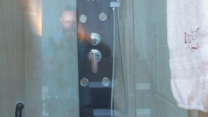 A glass-enclosed shower stall with a control panel, a towel rack, and a handrail. - Beautiful 2-Bed Apartment in Lekki (Lagos)