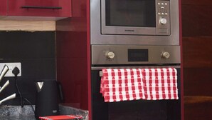 A kitchen with a microwave, oven, and red cabinets. - Beautiful 2-Bed Apartment in Lekki (Lagos)
